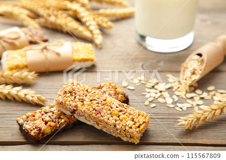 Healthy breakfast with granola bars and milk on grey wooden table. 115567809