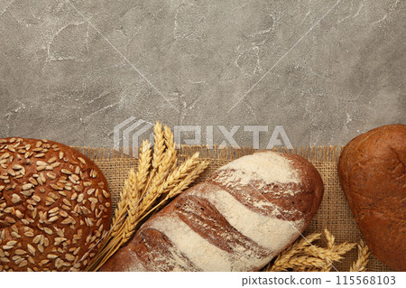 Fresh dark bread with spikelet of wheat on grey concrete table Fresh dark bread with spikelet of wheat on grey concrete table 115568103