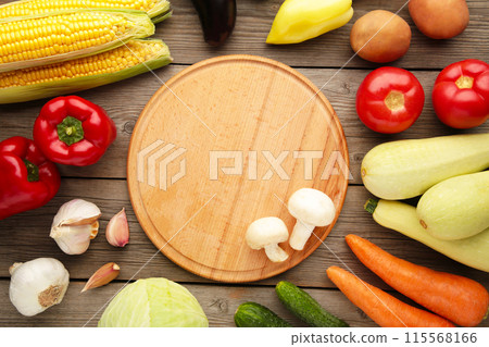 Image of a variety of colorful vegetables and cutting board on grey wooden background Image of a variety of colorful vegetables and cutting board on grey wooden background 115568166