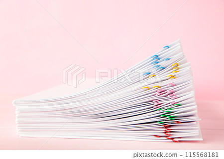 Colorful paper clip with pile of overload white paperwork on pink background 115568181