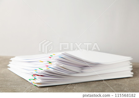 Stack of white paper with clips on grey background 115568182