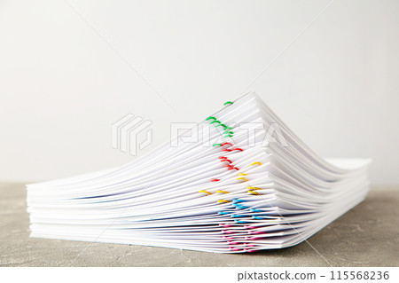 Stack of white paper with clips on grey background Stack of white paper with clips on grey background 115568236