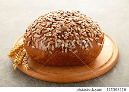 Wholegrain rye bread on a cutting board on grey background 115568256