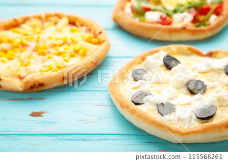 Variety of pizzas on blue wooden background 115568261
