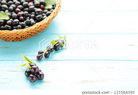 Basket with black currant on blue wooden background with copy space Basket with black currant on blue wooden background with copy space 115568393