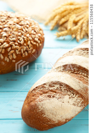 Fresh dark bread with spikelet of wheat on blue wooden table Fresh dark bread with spikelet of wheat on blue wooden table 115568438