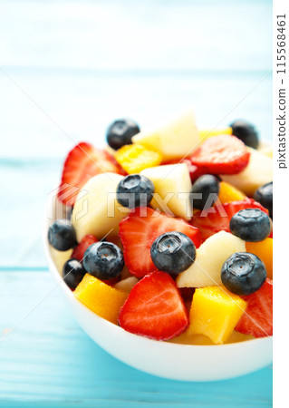 Fresh fruit salad in bowl on blue wooden background. Vertical foto Fresh fruit salad in bowl on blue wooden background. Vertical foto 115568461