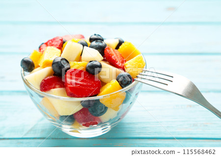 Fruit salad in a bowl with fork, served on the table. Fruit salad in a bowl with fork, served on the table. 115568462