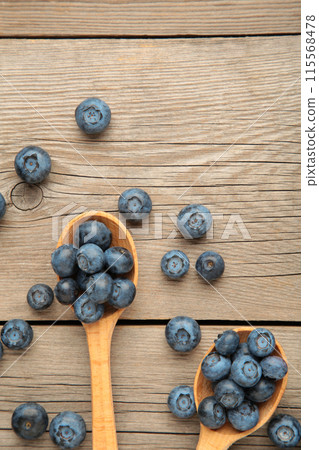 Fresh juicy blueberry fruits on a wooden spoons on grey background. Vertical foto Fresh juicy blueberry fruits on a wooden spoons on grey background. Vertical foto 115568478