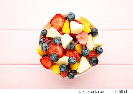 Salad with fresh fruits and berries on pink wooden background Salad with fresh fruits and berries on pink wooden background 115568513