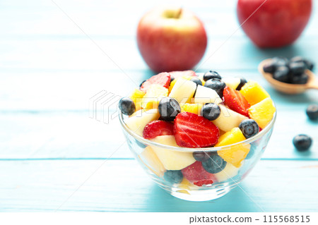 Salad with fresh fruits and berries on blue wooden background Salad with fresh fruits and berries on blue wooden background 115568515