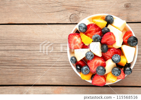 Salad with fresh fruits and berries on grey wooden background Salad with fresh fruits and berries on grey wooden background 115568516