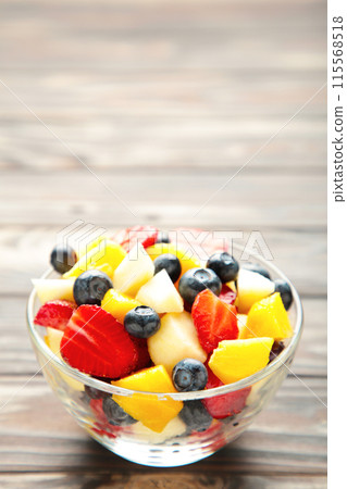 Fresh fruit salad in bowl on brown wooden background. Vertical foto 115568518