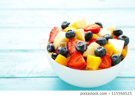 Salad with fresh fruits and berries on blue wooden background Salad with fresh fruits and berries on blue wooden background 115568525
