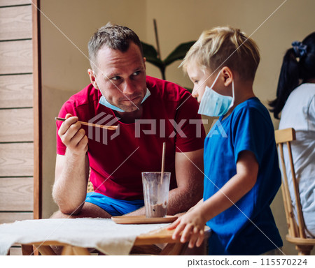 Father and son eat chocolate dessert with spoons in Cafe. Spending time together. Sweet tooth. Happy childhood Father and son eat chocolate dessert with spoons in Cafe. Spending time together. Sweet tooth. Happy childhood 115570224