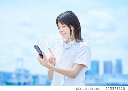 一位身穿白大褂、操作智慧型手機的年輕女子 一位身穿白大褂、操作智慧型手機的年輕女子 115571620
