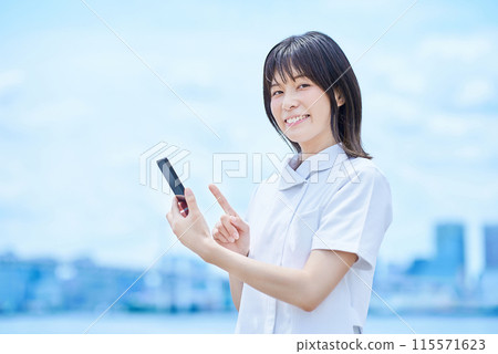 A young woman wearing a white coat operating a smartphone A young woman wearing a white coat operating a smartphone 115571623