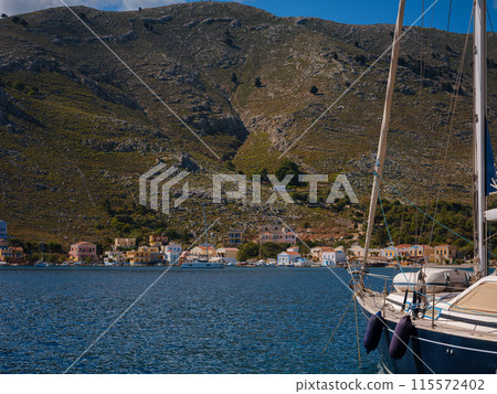 View on Symi or Simi island harbor port, classical ship yachts, houses on island hills, Aegean Sea bay. Greece islands holidays vacation travel tours from Rhodos island. Symi, Greece, Dodecanese. 115572402