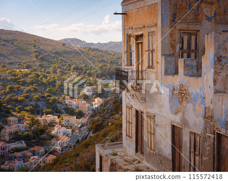 Symi Island, Greece. Greece islands holidays from Rhodos in Aegean Sea. Colorful neoclassical beautiful houses on hillsides of a Greek island during sunset. Holiday travel background. Symi Island, Greece. Greece islands holidays from Rhodos in Aegean Sea. Colorful neoclassical beautiful houses on hillsides of a Greek island during sunset. Holiday travel background. 115572418