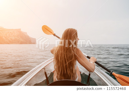 Woman in kayak back view. Happy young woman with long hair floating in transparent kayak on the crystal clear sea. Summer holiday vacation and cheerful female people relaxing having fun on the boat 115572468