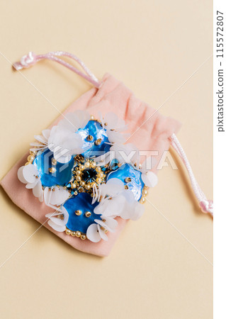Handmade blue mother-of-pearl brooch on a plush bag 115572807