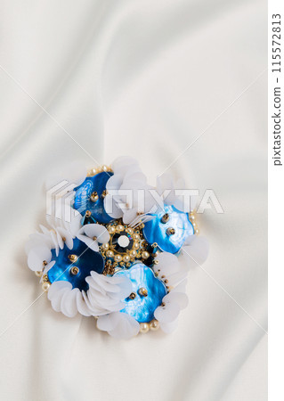 Handmade blue mother-of-pearl brooch on a white cloth Handmade blue mother-of-pearl brooch on a white cloth 115572813