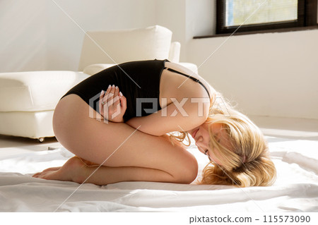 Young sullen woman in lingerie lies on bed 115573090