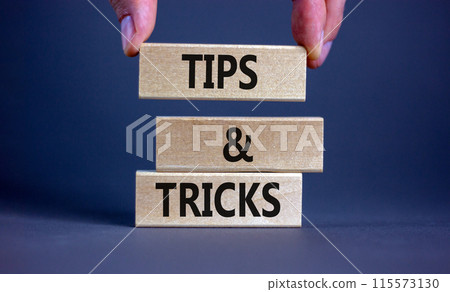 Tips and tricks symbol. Wooden blocks with words 'Tips and tricks'. Beautiful grey background. businessman hand. Business, tips and tricks concept. Copy space. 115573130