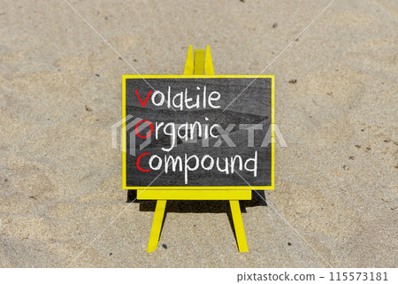 VOC volatile organic compound symbol. Concept words VOC volatile organic compound on beautiful yellow blackboard. Beautiful sand background. Business VOC volatile organic compound concept. Copy space 115573181