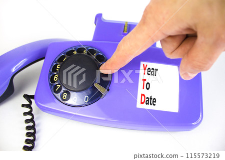 YTD year to date symbol. Concept words YTD year to date on beautiful old disk phone. Beautiful white background. Businessman hand. Business YTD year to date concept. Copy space. 115573219