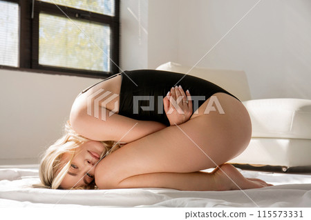 Young sullen woman in lingerie lies on bed 115573331