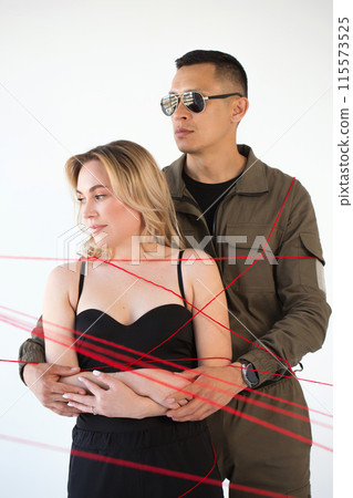 A young couple, a man and a woman, are wrapped in red threads. Dependency concept 115573525