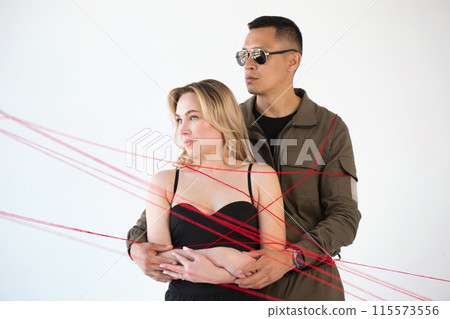 A young couple, a man and a woman, are wrapped in red threads. Dependency concept 115573556