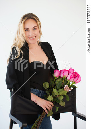 A beautiful woman in a black suit with a bouquet of roses A beautiful woman in a black suit with a bouquet of roses 115573561