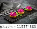 dessert of baked buns with raspberry topping and seed decorations, side view 115574383