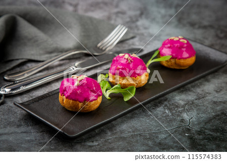 dessert of baked buns with raspberry topping and seed decorations, side view 115574383