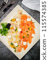 sliced red and white fish with mozzarella cheese and herbs, top view 115574385