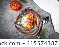 side view of a dish of baked persimmons, colored peppers, rice and seeds 115574387