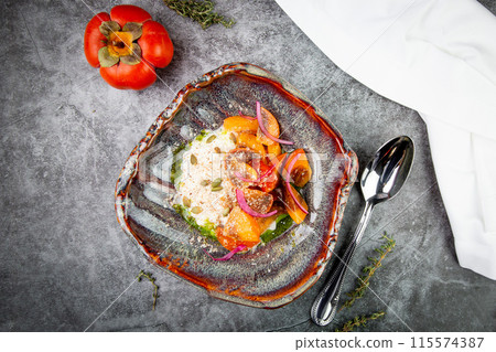 side view of a dish of baked persimmons, colored peppers, rice and seeds side view of a dish of baked persimmons, colored peppers, rice and seeds 115574387