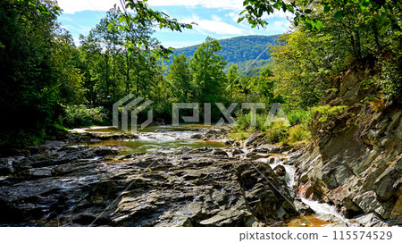 The flow of a mountain river among the stone rocks The flow of a mountain river among the stone rocks 115574529