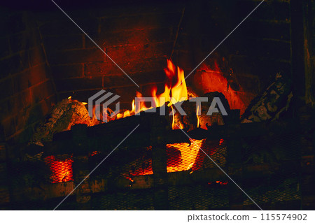 Burning wood in a brick fireplace in the dark Burning wood in a brick fireplace in the dark 115574902