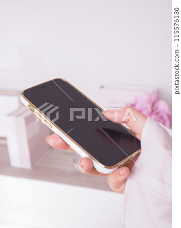 一位女性操作智慧型手機的手和一間內部女性化的房間 一位女性操作智慧型手機的手和一間內部女性化的房間 115576180