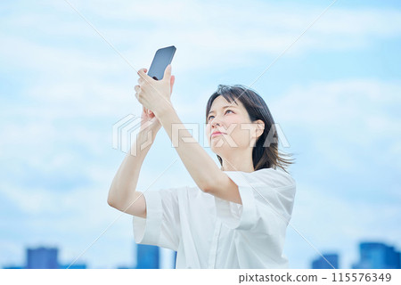 A young woman operating a smartphone 115576349