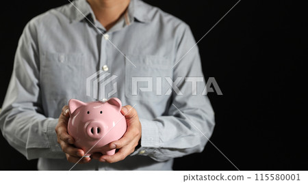Business man hand hold piggy bank on black background with copy space, business investment Business man hand hold piggy bank on black background with copy space, business investment 115580001