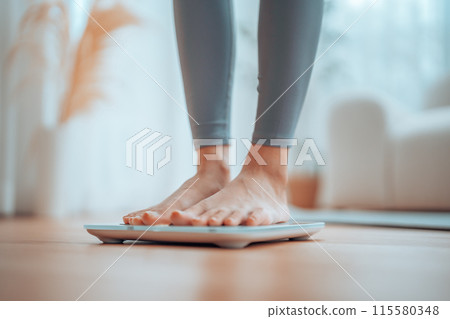 Closeup of feet, Young Asian woman standing on scales to measure her weight at home 115580348