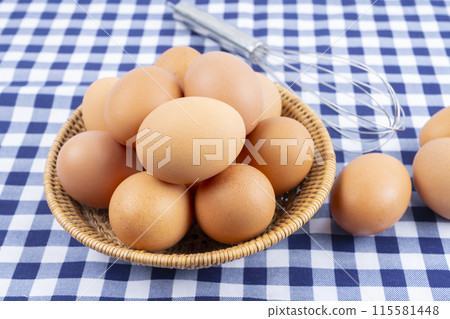 The Fresh raw eggs in the basket on blue tablecloth The Fresh raw eggs in the basket on blue tablecloth 115581448