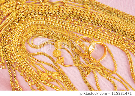 Many gold necklaces on pink velvet cloth. 115581471