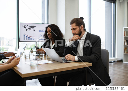 Diverse team in a focused business meeting with technology 115582461