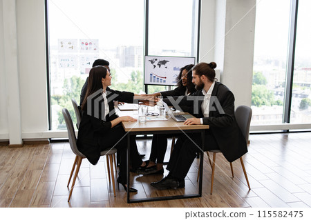 Business people holding hands together in meeting room 115582475