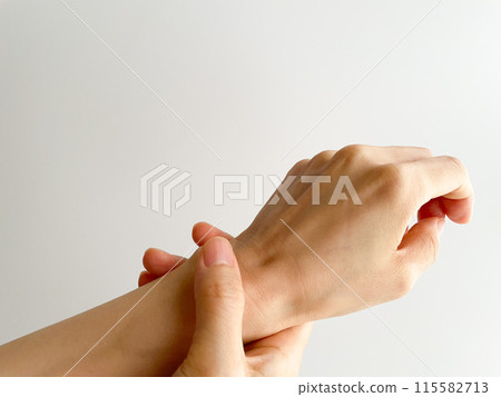 A woman's hand holding her left wrist with her right hand 115582713